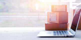 A laptop is sitting next to shipping packages A laptop is sitting next to shipping packages